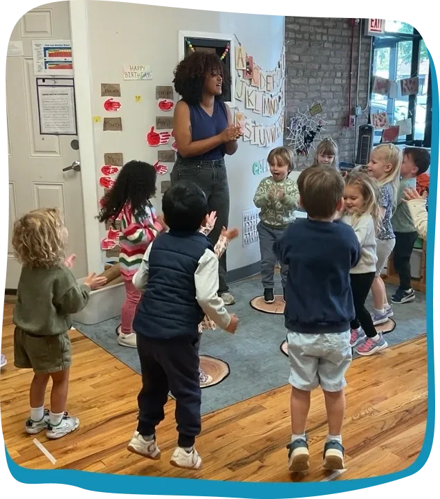 A Songbird Academy teacher leads toddlers in a movement activity in the classroom