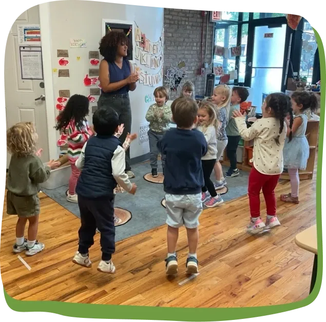 A Songbird Academy teacher leads children in yoga and movement in the classroom